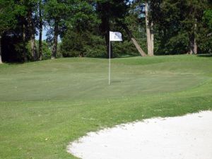 Flag blows in the wind on green with bunker in front